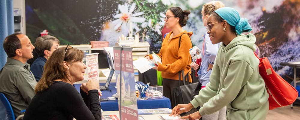 Students meeting with representatives from regional four-year colleges during a transfer event.